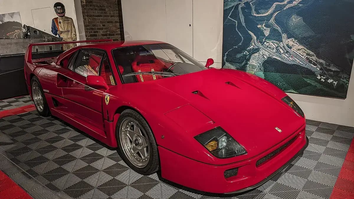 The red Ferrari F40 on display in the Spa-Francorchamps Circuit Museum, in front of an aerial view of the circuit